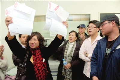 购房者高举当初的选房申请书,里面记载的优惠项目也一度被开发商抹去。