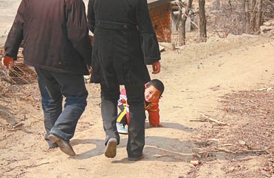 代课教师张良、段文静夫妻俩和孩子在家旁边的山坡上散步,三岁的儿子淘气地跑来跑去。